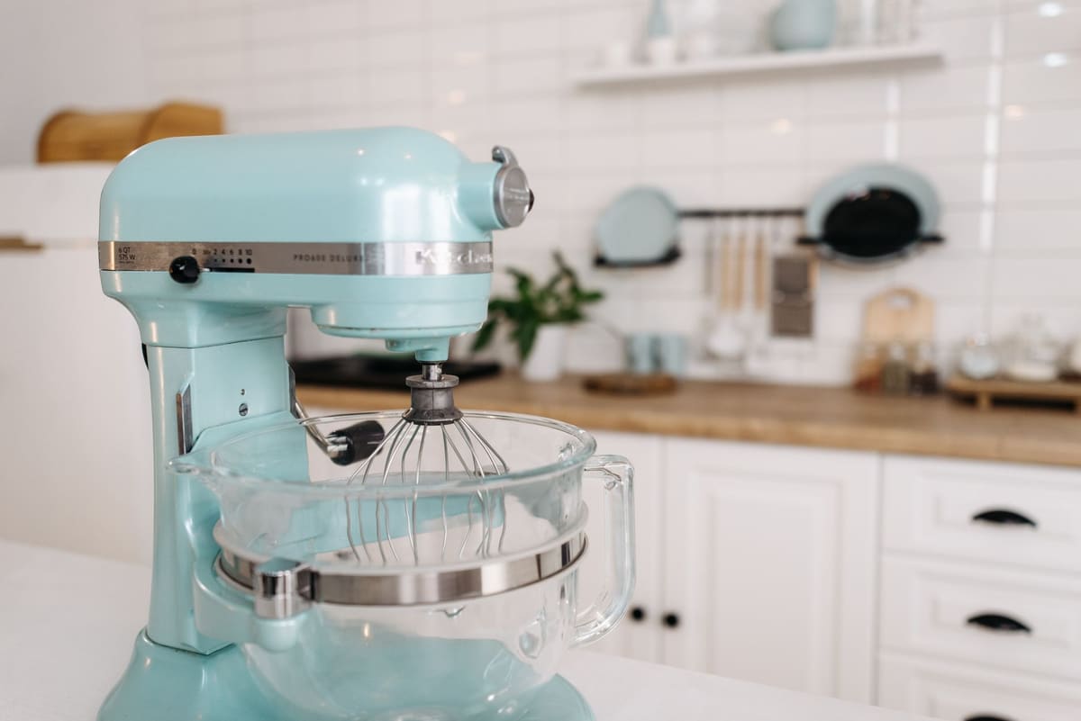 Robot pâtissier posé sur un plan de travail à côté d'accessoires de pâtisserie